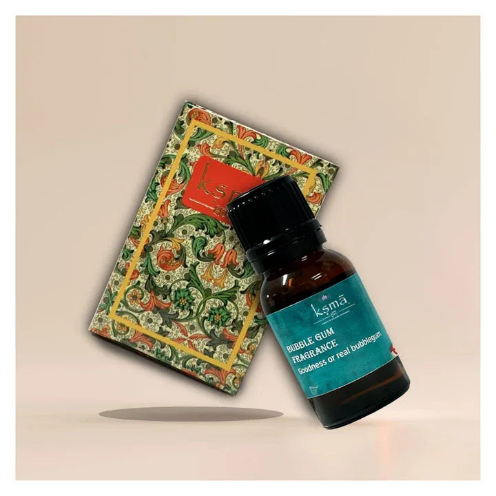 Bubblegum fragrance oil bottle placed with decorative patterned book on neutral background